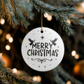 Front view of White ceramic Christmas ornament with graphic displaying stars, angels, and text that says Merry Christmas hanging in a tree