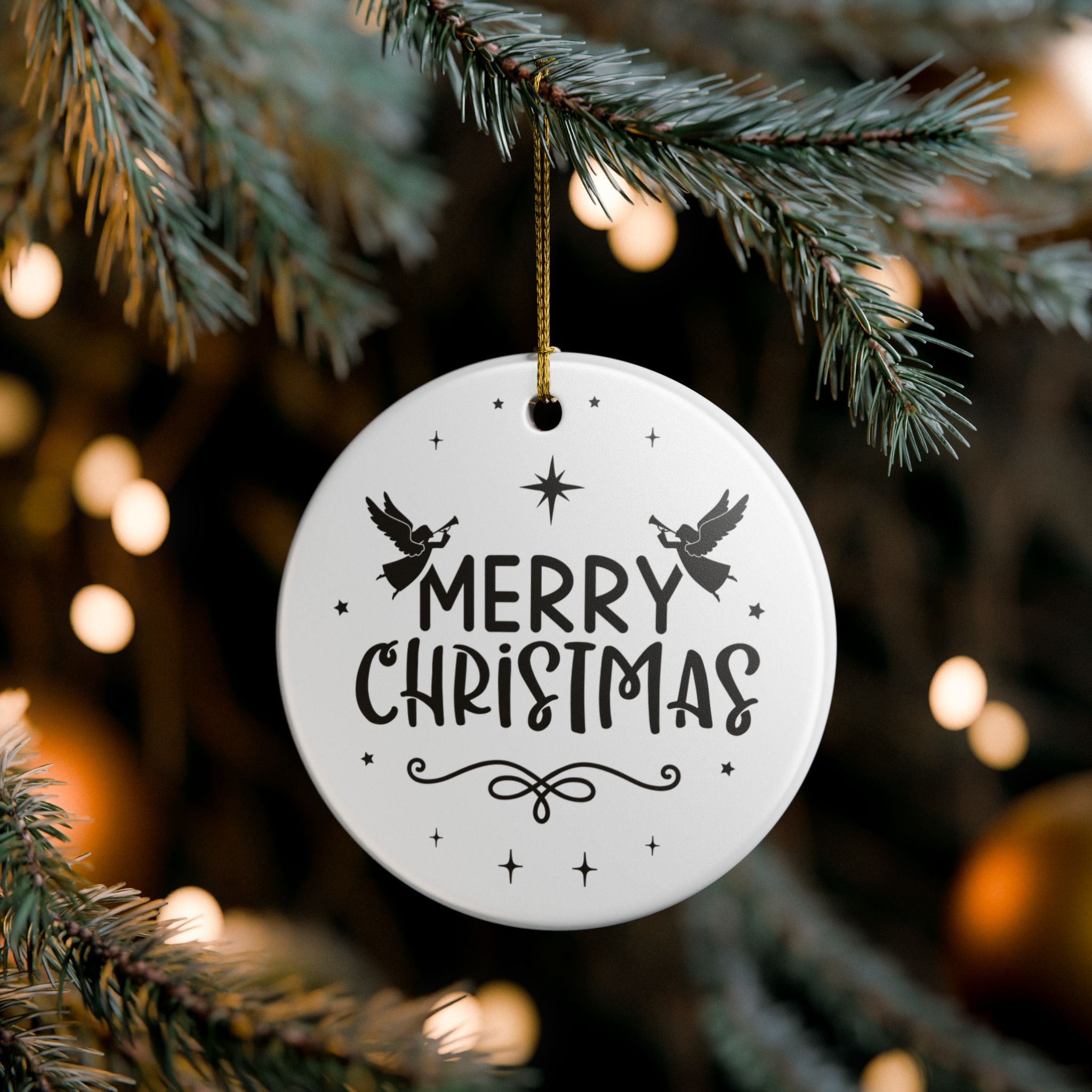 Front view of White ceramic Christmas ornament with graphic displaying stars, angels, and text that says Merry Christmas hanging in a tree