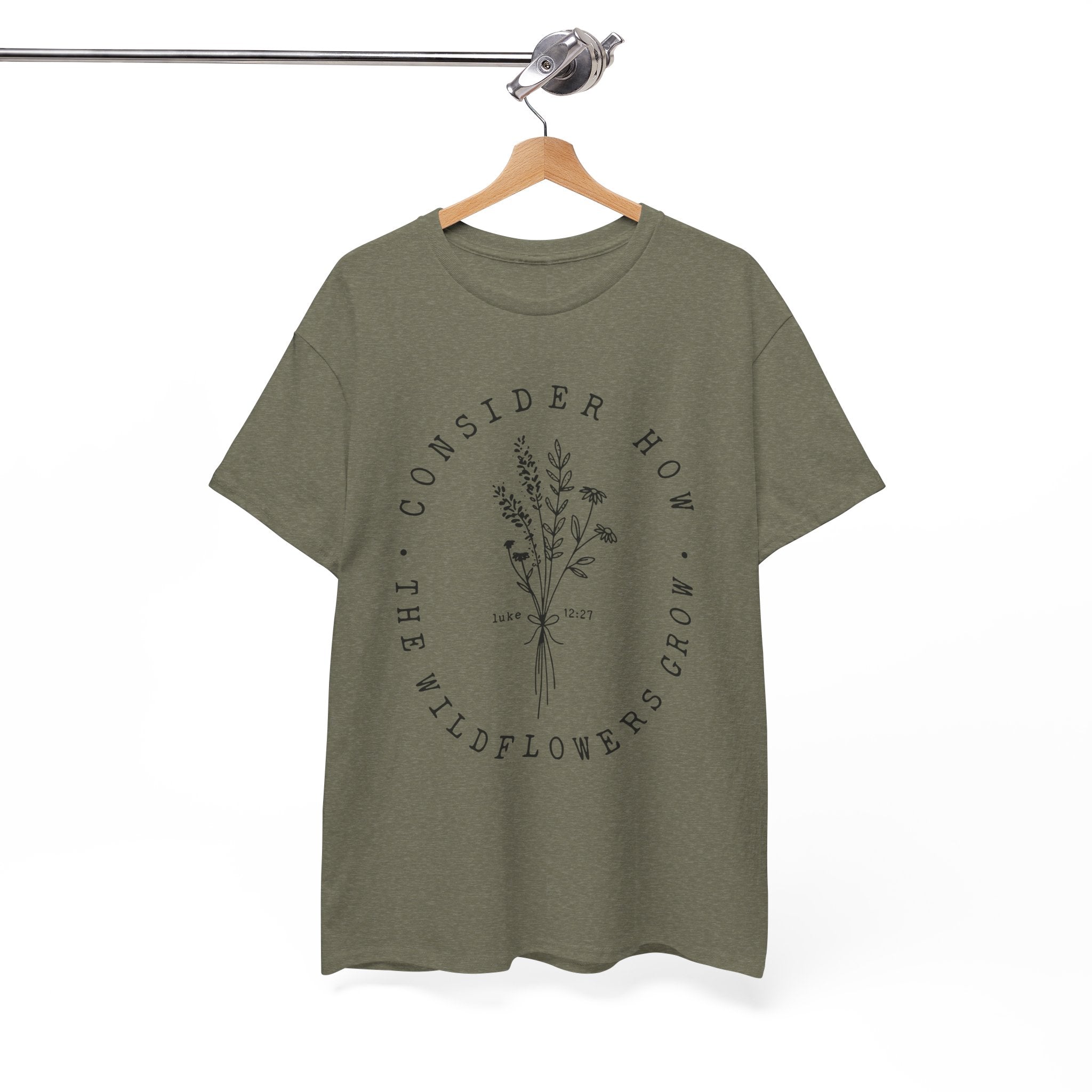 Front view Heather Military Green t-shirt with large black floral graphic and Luke 12:27 Bible verse displayed on a hanger