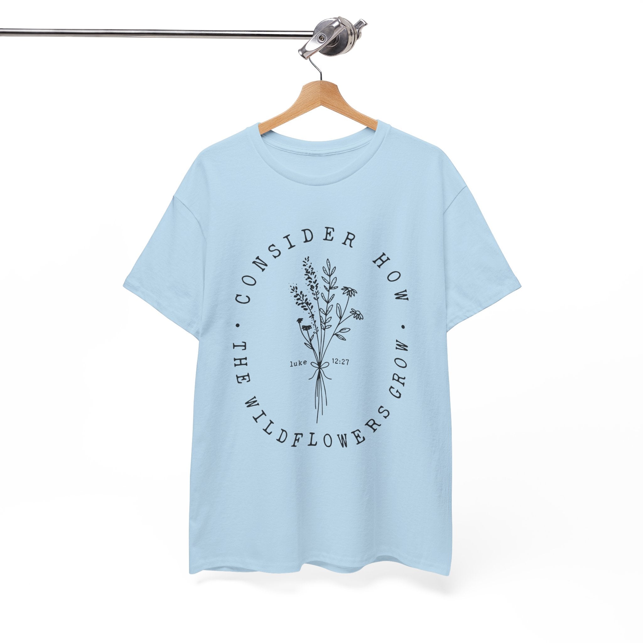 Front view Light Blue t-shirt with large black floral graphic and Luke 12:27 Bible verse displayed on a hanger