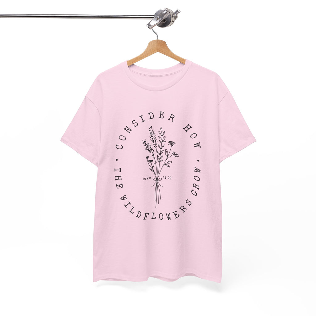 Front view Light Pink t-shirt with large black floral graphic and Luke 12:27 Bible verse displayed on a hanger