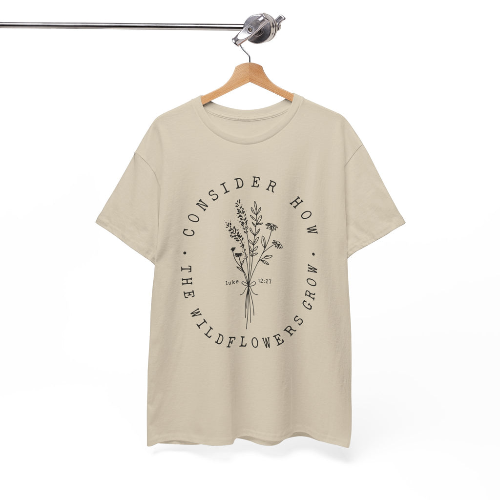 Front view Sand t-shirt with large black floral graphic and Luke 12:27 Bible verse displayed on a hanger