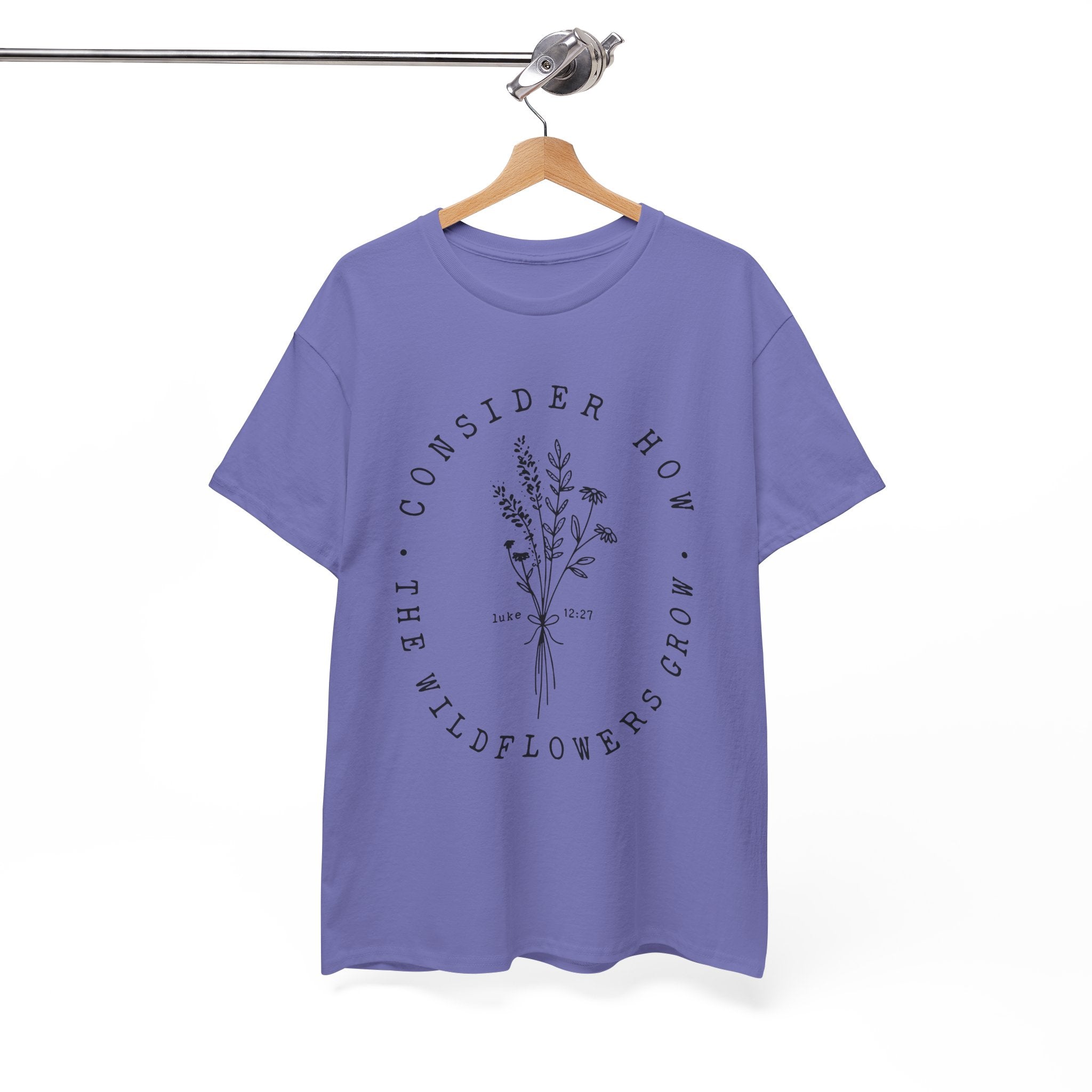 Front view Violet t-shirt with large black floral graphic and Luke 12:27 Bible verse displayed on a hanger
