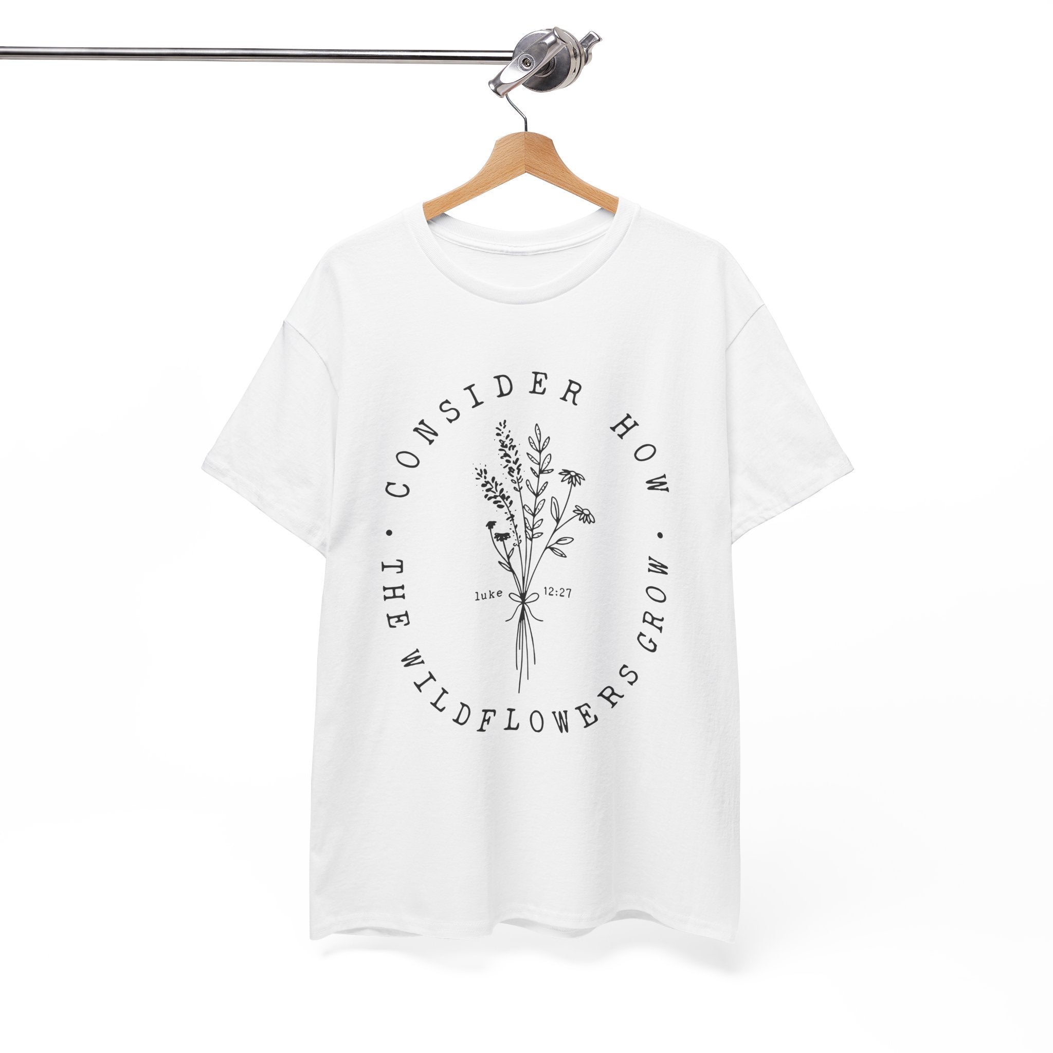 Front view White t-shirt with large black floral graphic and Luke 12:27 Bible verse displayed on a hanger