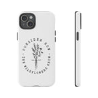 White iPhone case with black floral graphic and Luke 12:27 Bible verse displayed on an iPhone 15 Plus