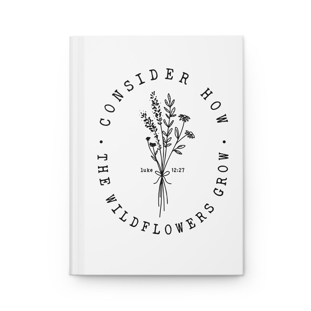 front view of white hardcover journal with black floral graphic and Bible verse from Luke 12:27 