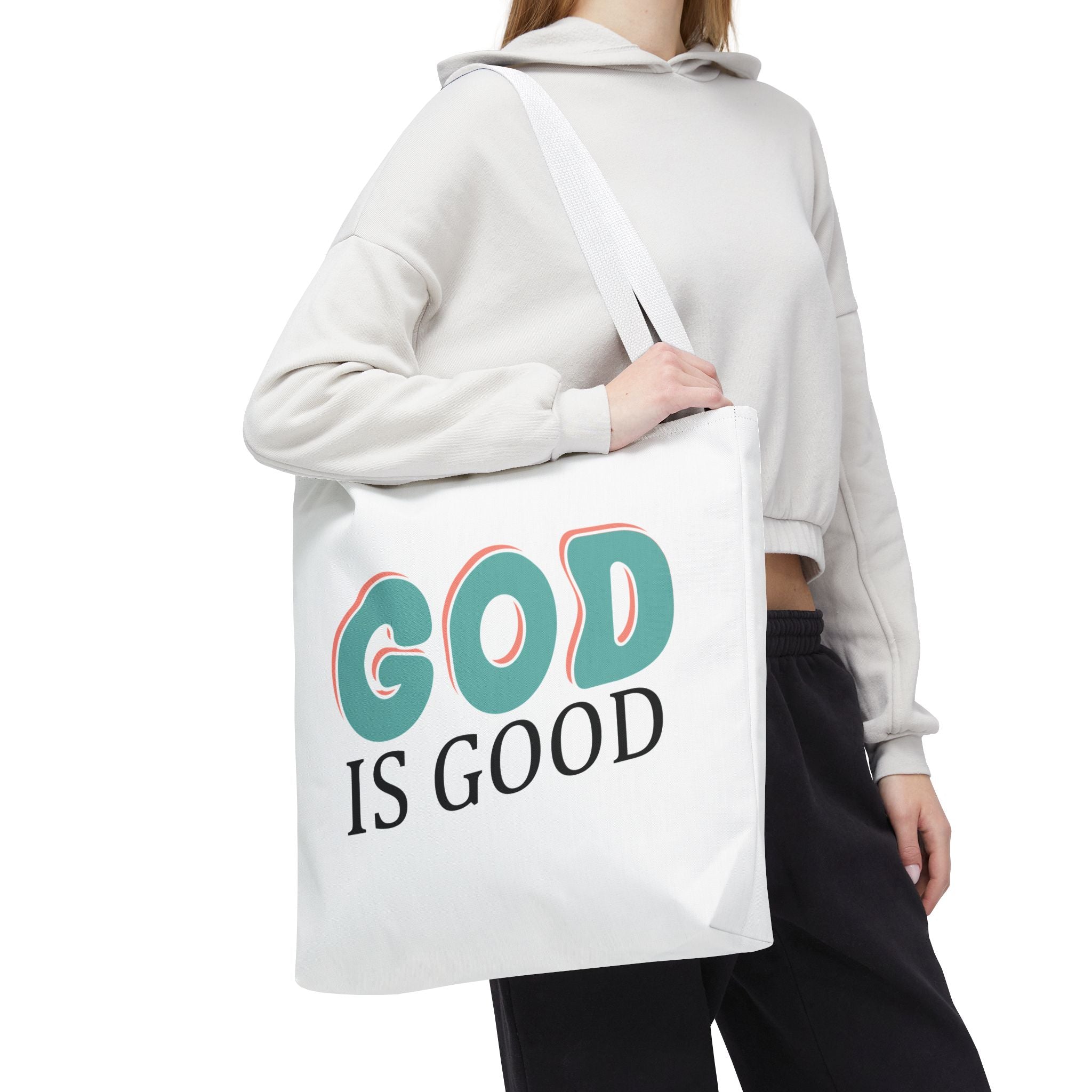 Front view of large White tote bag with white handles, colorful graphic that says God is Good, displayed over model’s shoulder