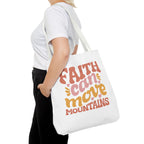 Front view of large White tote bag with white handles, colorful graphic that says Faith Can Move Mountains, displayed over model’s shoulder