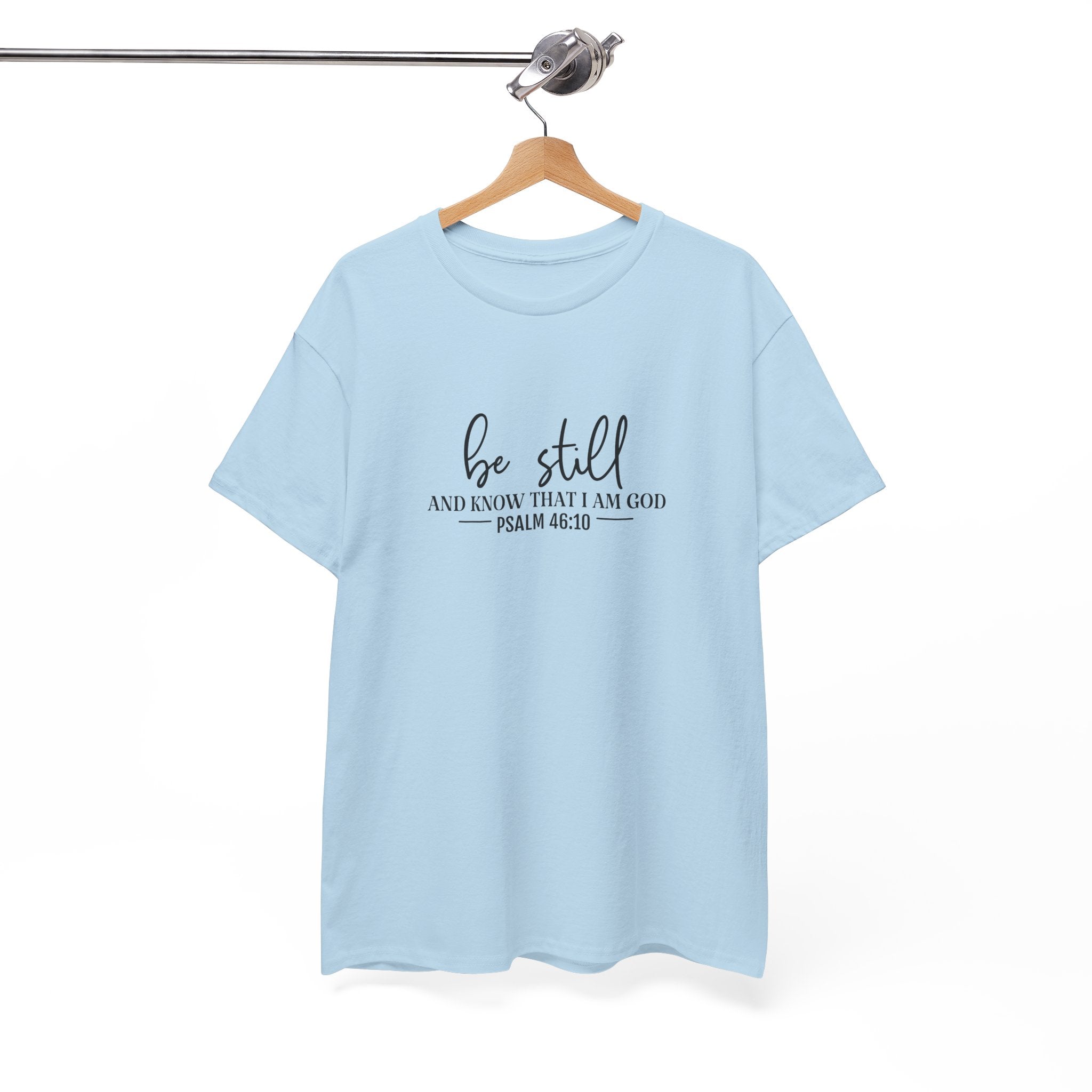 Front view of Light Blue t-shirt with black text Be Still And Know That I Am God Psalm 46:10 centered on chest. Shirt is displayed on a hanger.