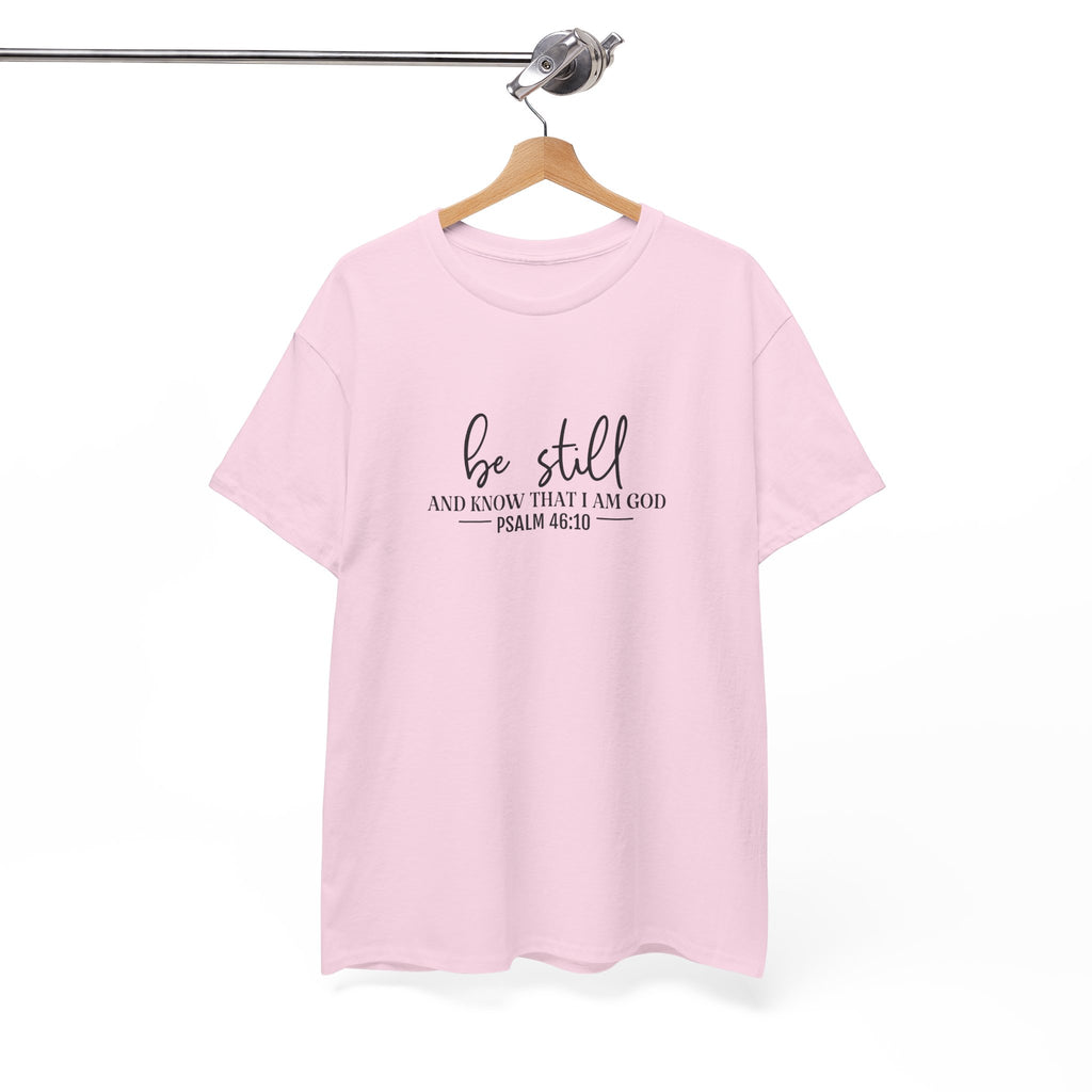 Front view of Light Pink t-shirt with black text Be Still And Know That I Am God Psalm 46:10 centered on chest. Shirt is displayed on a hanger.