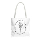 Front view of medium White tote bag with white handles and large black floral graphic and Luke 12:27 Bible verse