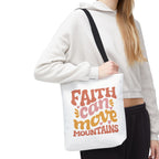 Front view of small White tote bag with black handles, colorful graphic that says Faith Can Move Mountains, displayed over model’s shoulder
