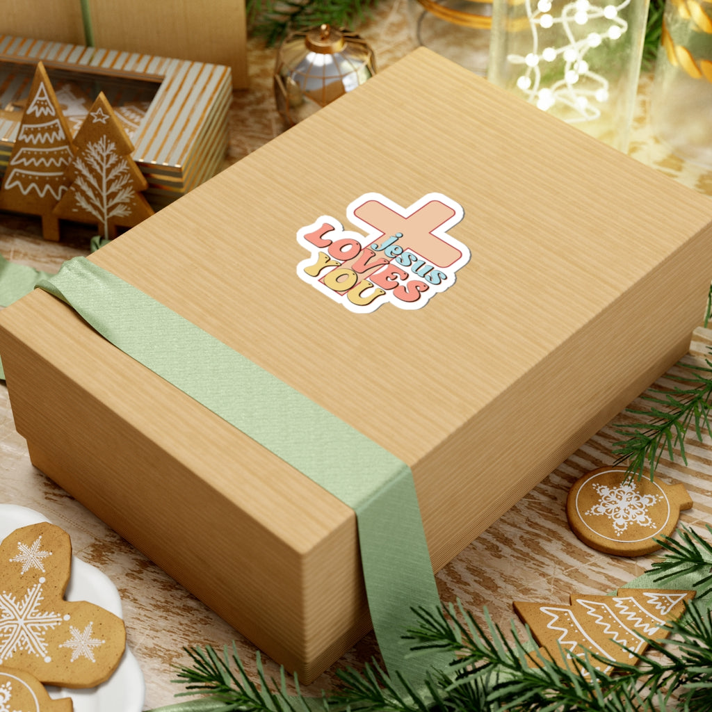 Sticker with colorful graphic and text saying Jesus Loves You. Displayed on gift box.