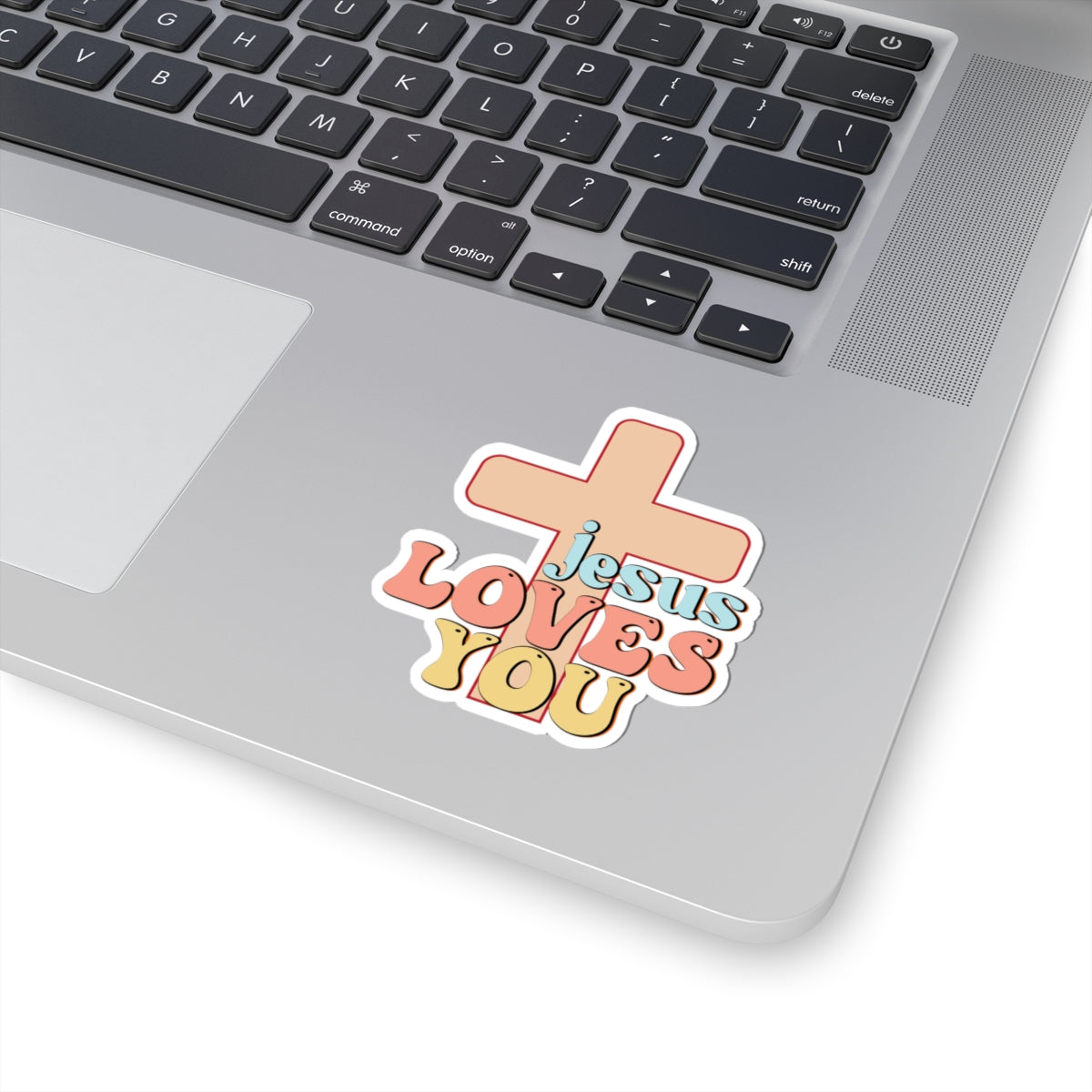 Sticker with colorful graphic and text saying Jesus Loves You. Displayed on laptop.