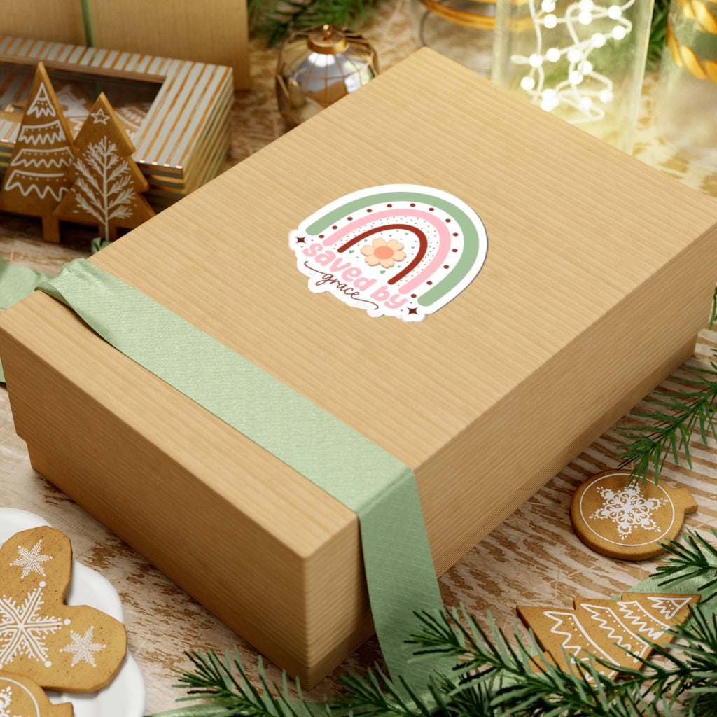Sticker with pastel colored rainbow graphic with the text Saved by Grace. Displayed on gift box.