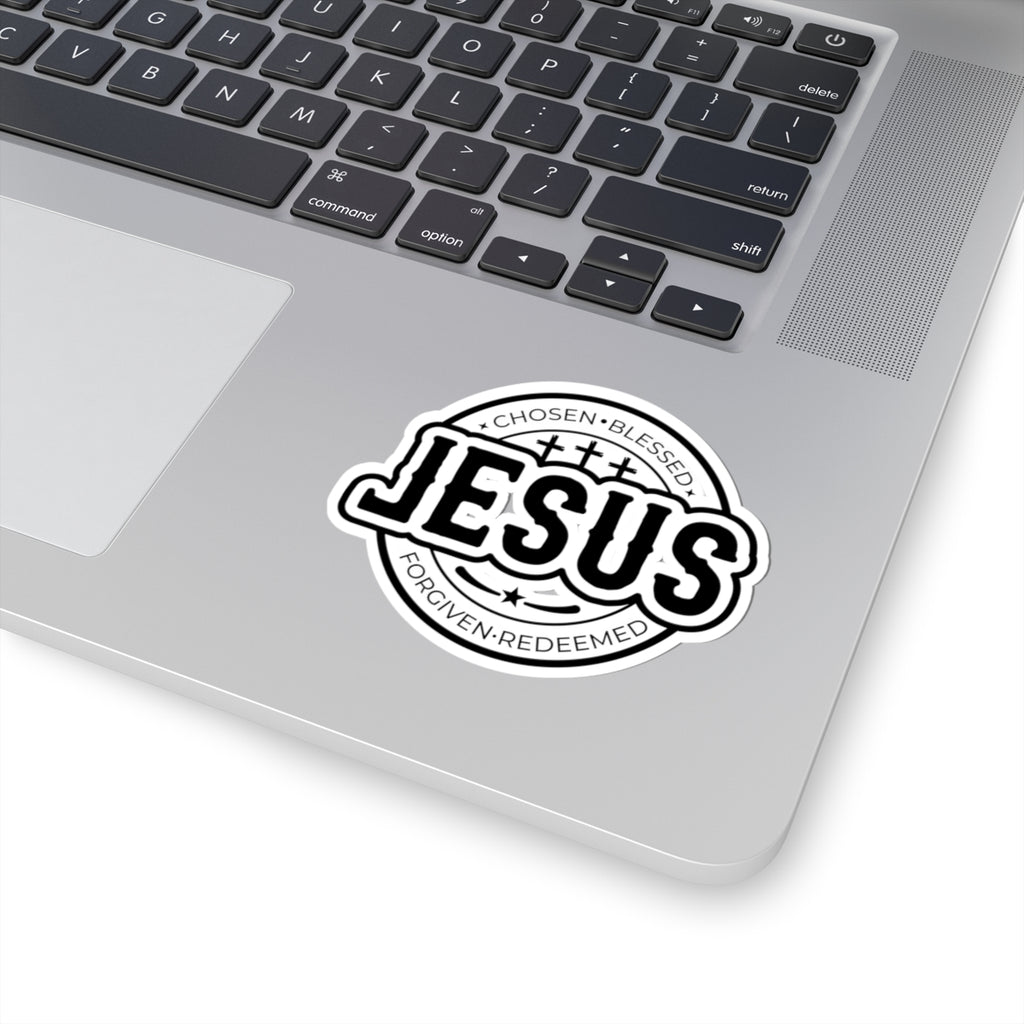 Sticker with large JESUS text surrounded by religious words. Displayed on laptop.