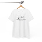 Front view of white t-shirt with black text Be Still And Know That I Am God Psalm 46:10 centered on chest. Shirt is displayed on a hanger.