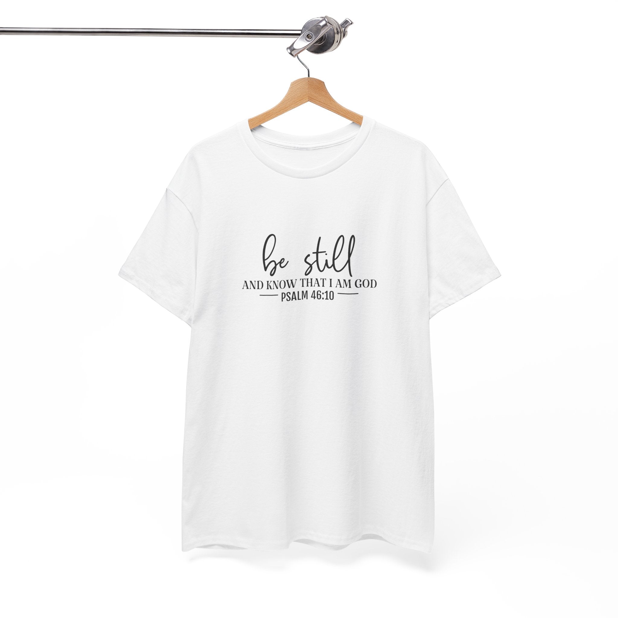 Front view of white t-shirt with black text Be Still And Know That I Am God Psalm 46:10 centered on chest. Shirt is displayed on a hanger.