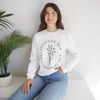 Front view White crewneck sweatshirt black floral graphic and 'Consider How the Wildflowers Grow' text from Bible verse Luke 12:27. Displayed on a model.